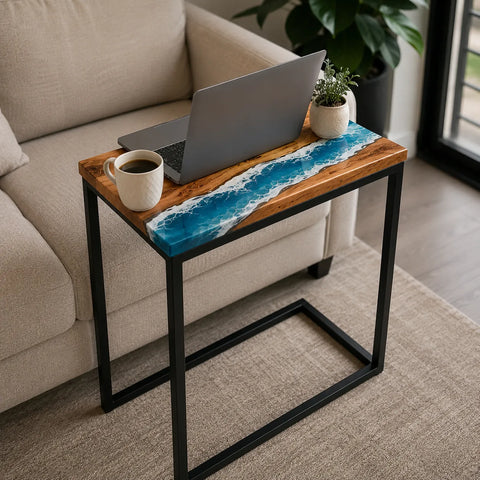 Small wooden table with a blue resin design next to a beige sofa, featuring a laptop and cup.