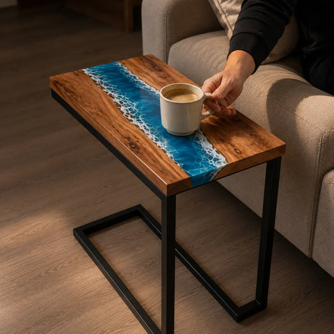 Wooden side table with blue resin design next to a person holding a coffee cup.