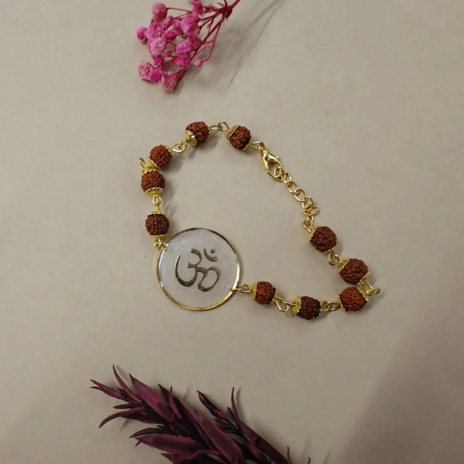 Bracelet with gold chain and brown beads on a beige background