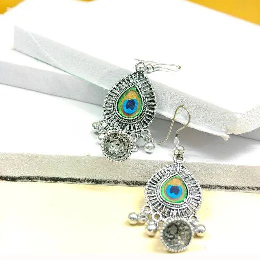 Pair of silver earrings with peacock feather design on a white ribbon