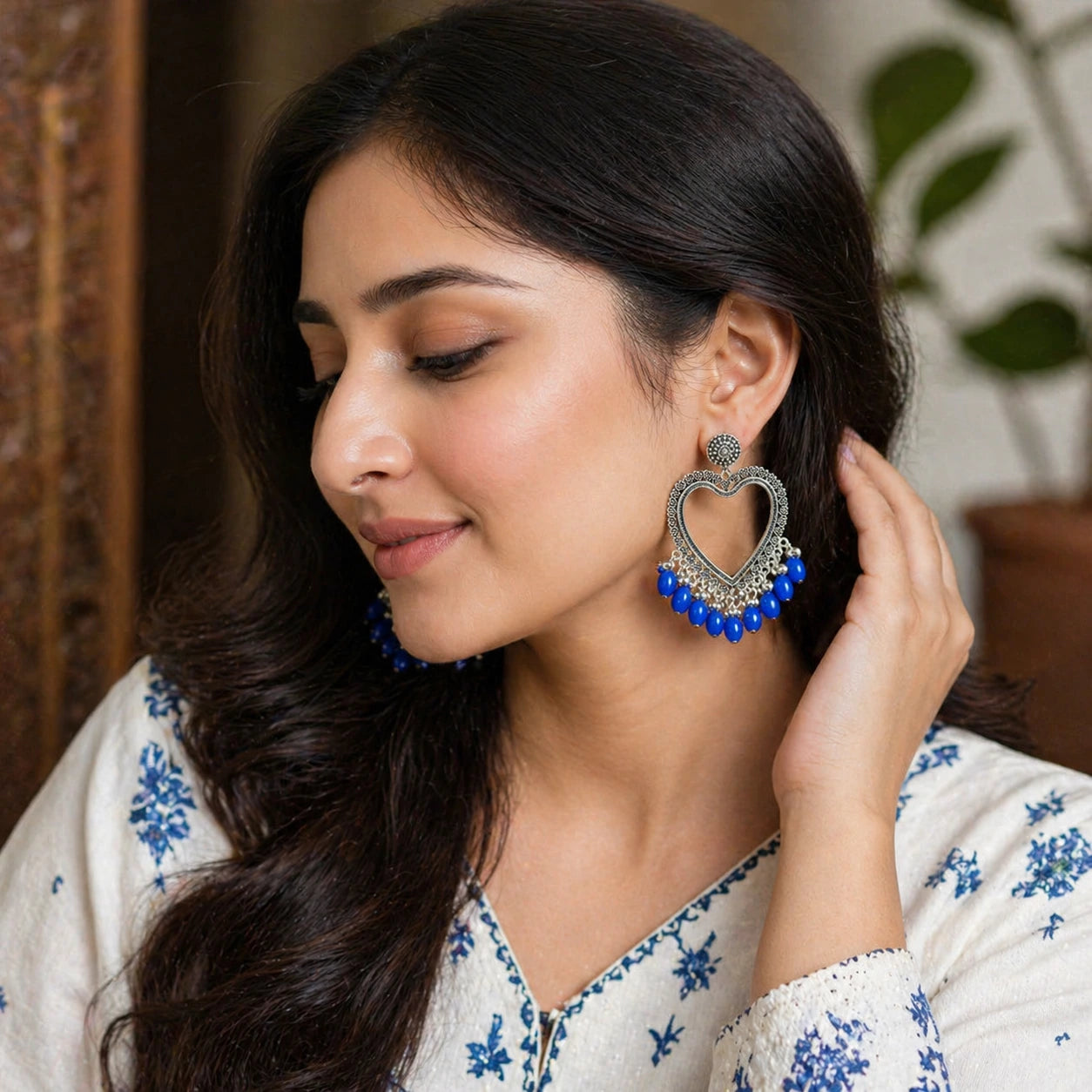 Woman wearing a pair of large, decorative earrings with blue beads.