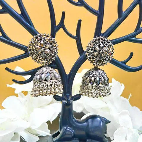 Decorative earrings on a blue deer-shaped stand with a yellow background