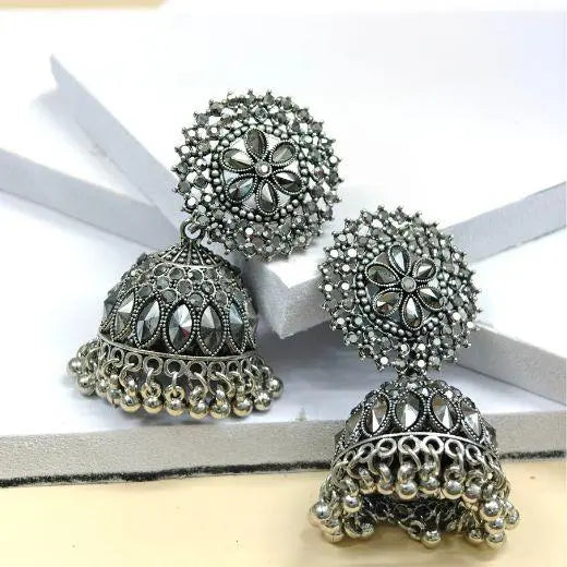 Pair of silver jhumka earrings on a white ribbon background