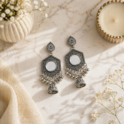 Ornate silver earrings on a light marble surface with decorative elements.