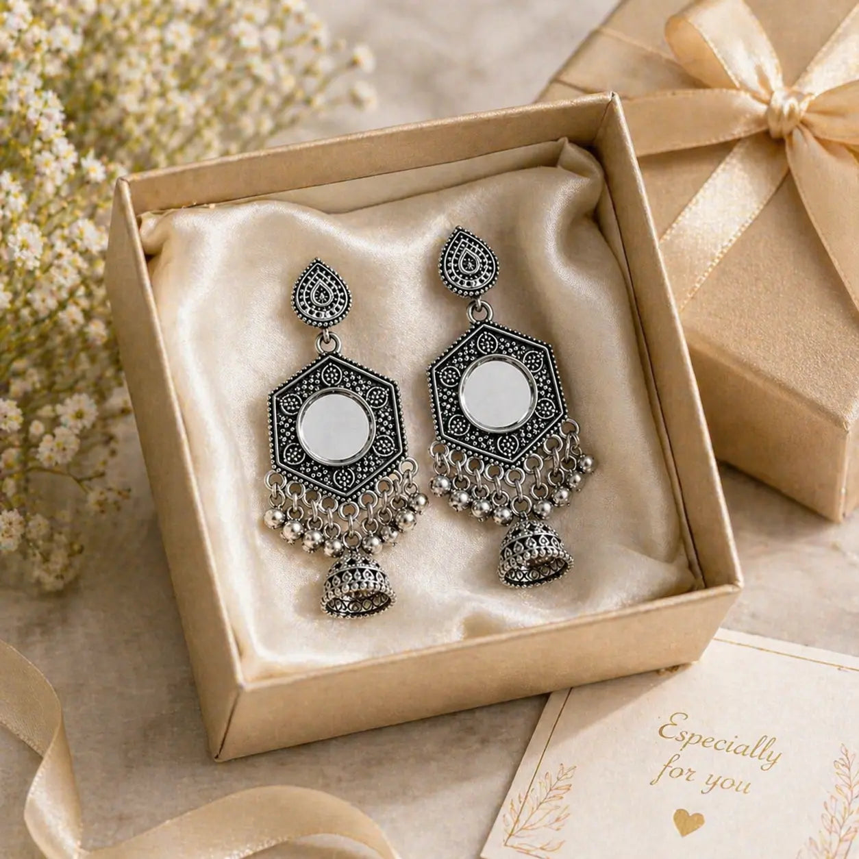 Ornate earrings in a decorative box with a bow and card on a light background