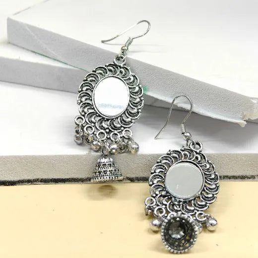 Pair of silver earrings with mirror-like centers on a white surface