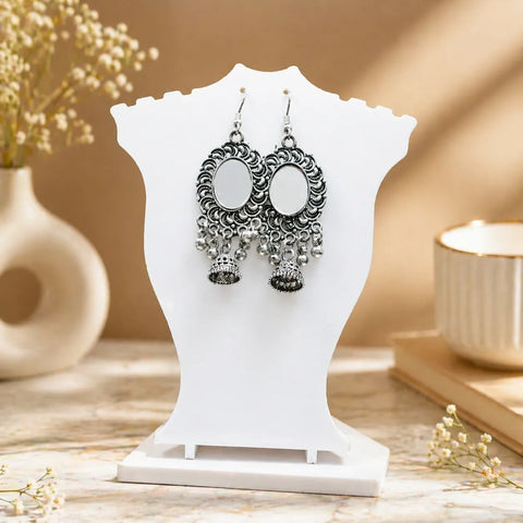 Oxidised silver mirror jhumka earrings displayed on white jewellery stand with intricate ethnic design
