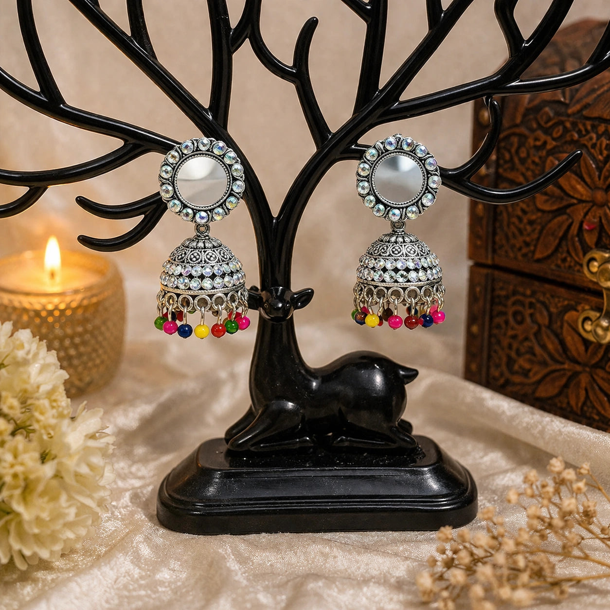 Jewelry tree with decorative earrings and a candle in the background