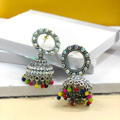 Ornate earrings with colorful beads on a white surface with a yellow background