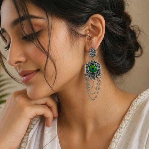 Close-up of a woman wearing an ornate earring with a green gemstone.