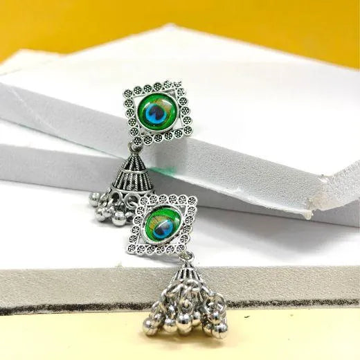 Pair of silver earrings with green gemstones on a white and yellow background