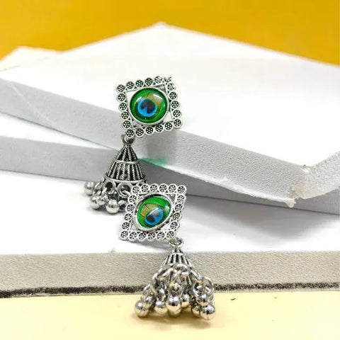 Pair of silver earrings with green gemstones on a white and yellow background