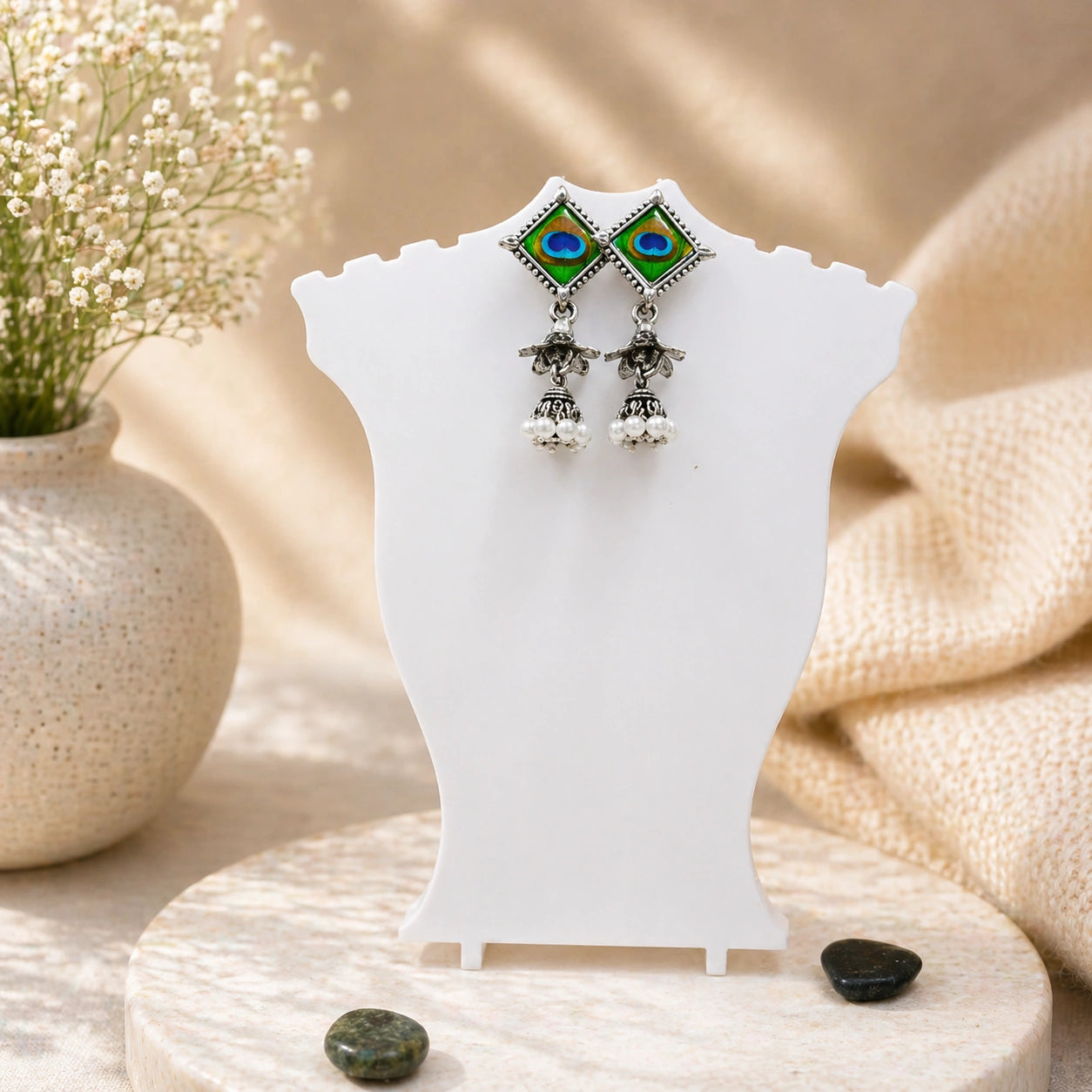 Pair of earrings on a white stand with a natural background