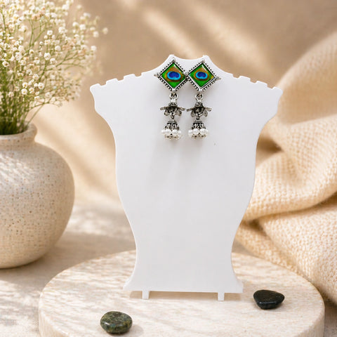 Pair of earrings on a white stand with a natural background