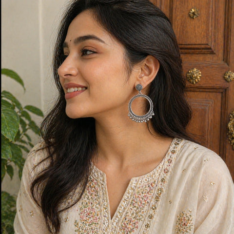 Woman wearing large hoop earrings with a neutral background