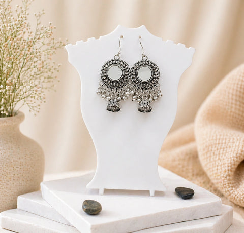 Silver earrings on a white jewelry stand with a neutral background