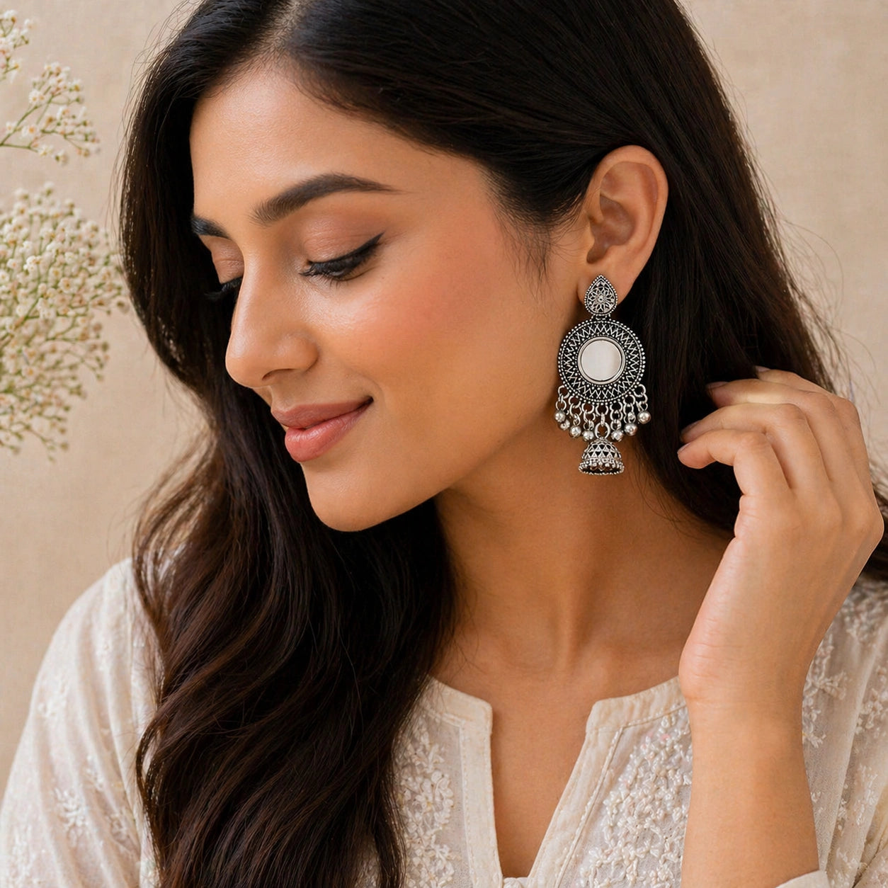 Woman wearing a silver earring with a beige background