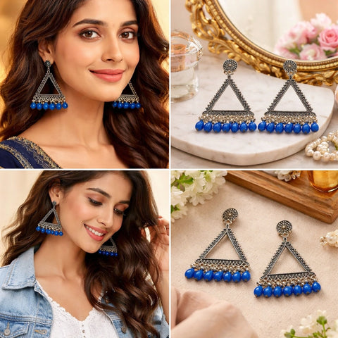 Triangular earrings with blue beads on a model and a decorative surface.