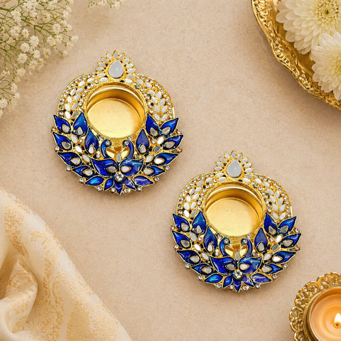 Pair of gold and blue decorative earrings on a beige background with flowers.