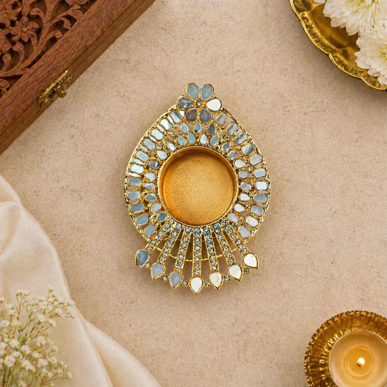 Decorative gold and stone tealight holder on a beige surface with flowers.