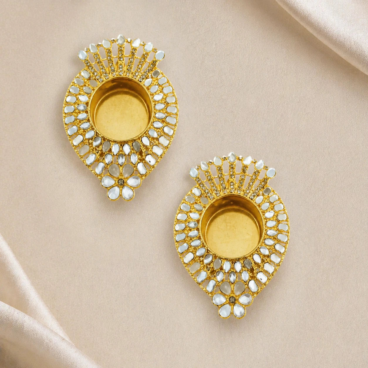Pair of gold earrings with gemstone accents on a beige fabric background