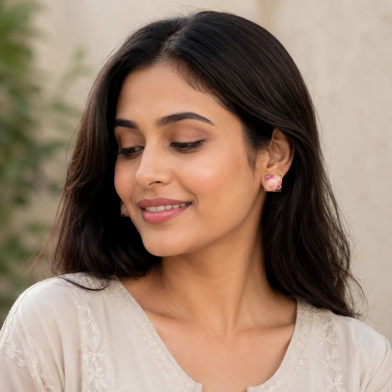Handmade pink floral resin square stud earrings worn by an Indian woman in a soft natural daylight lifestyle fashion look