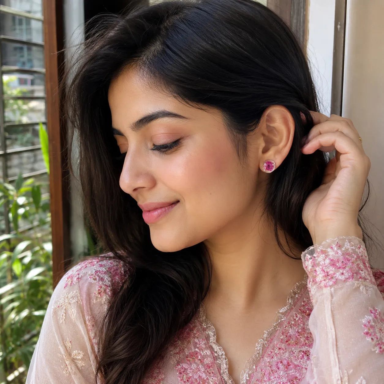 Indian woman wearing handmade pink floral resin stud earrings with real dried flower detailing in a natural daylight lifestyle fashion look.