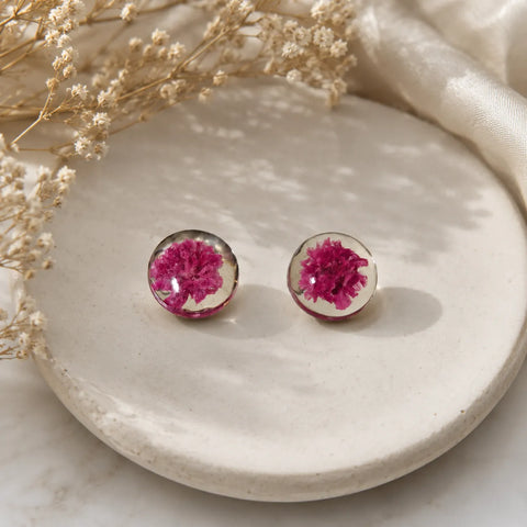 Handmade pink floral resin stud earrings with real dried flower detailing displayed on a ceramic tray with soft luxury aesthetic styling.