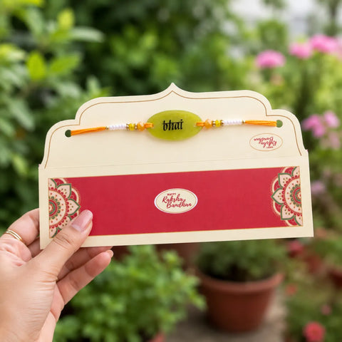 Rakhi with a card held in front of a blurred garden background