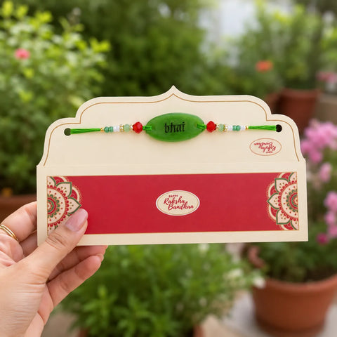 Rakhi with a card held by a hand against a blurred green outdoor background
