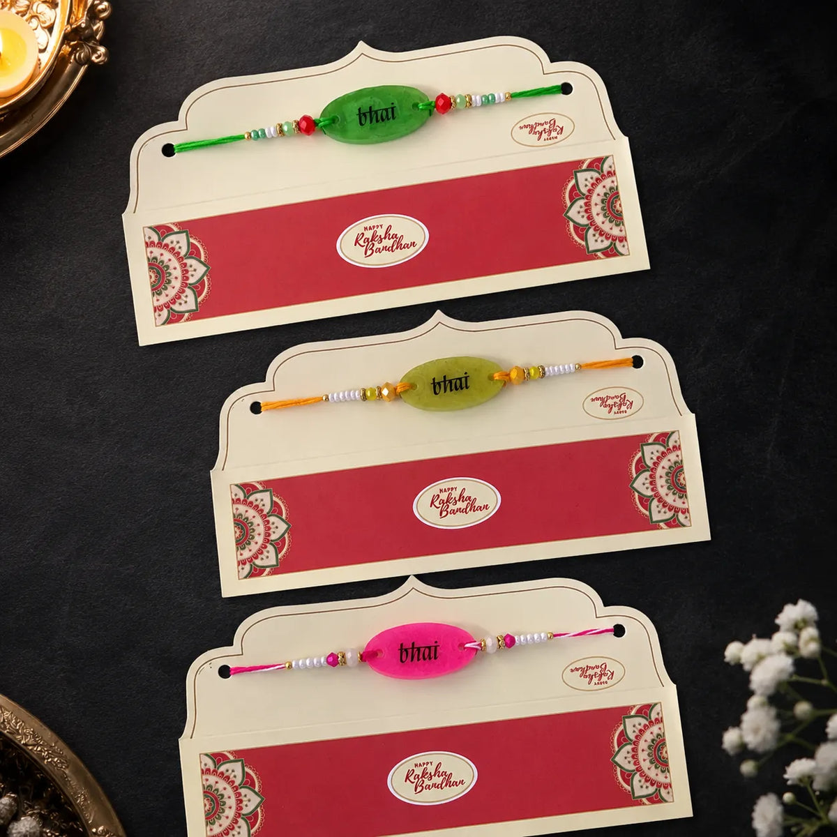 Three decorative cards with colorful rakhi ribbons on a dark background