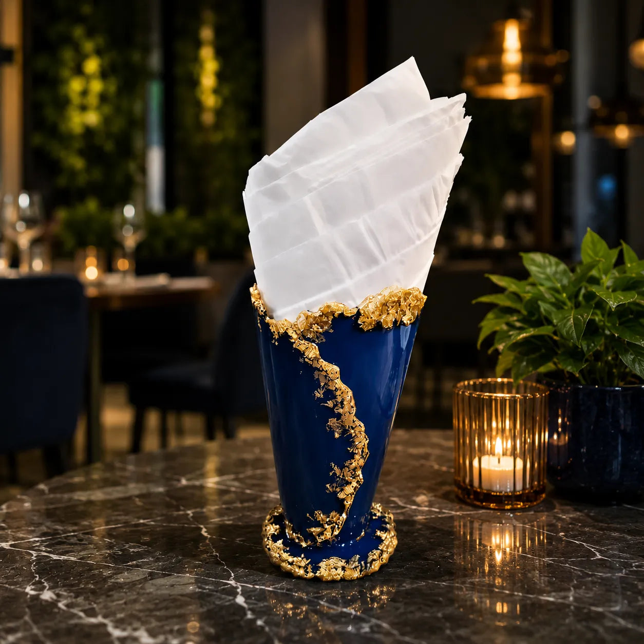 Decorative blue and gold vase with a white cloth on a marble table in an elegant setting.