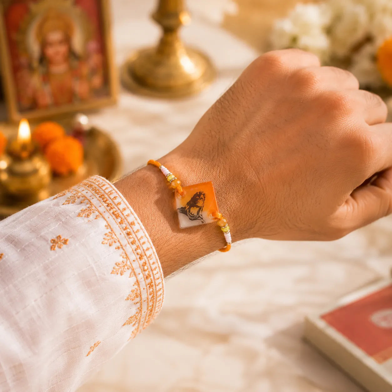Hand wearing a bracelet with a butterfly design, set against a blurred background of religious items.