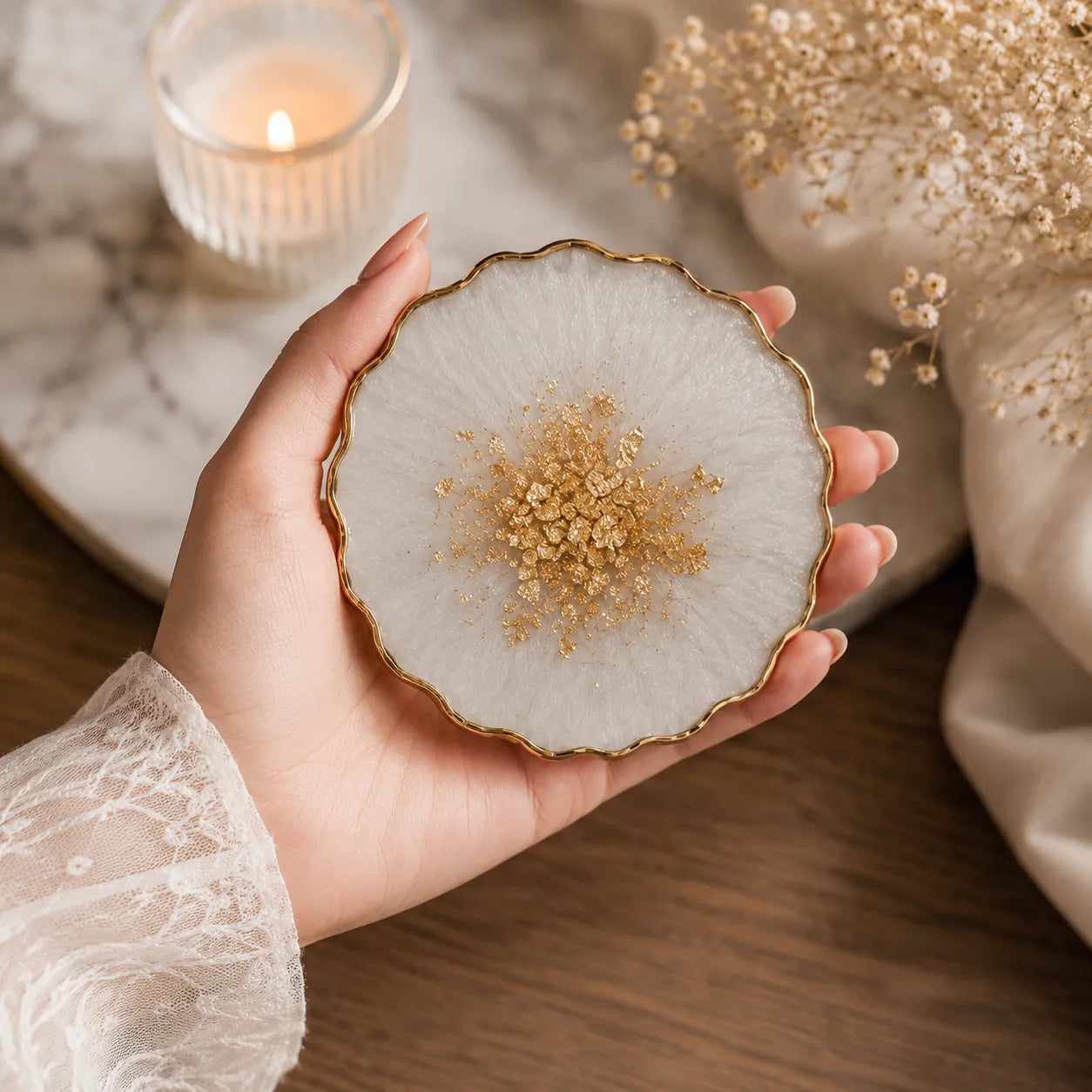 Hand holding a decorative plate with gold embellishments on a wooden surface.