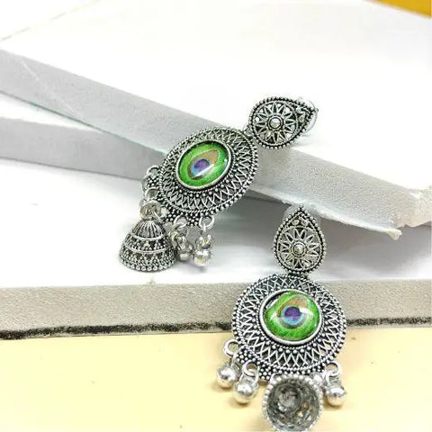 Ornate silver earrings with green gemstones on a white and gray background