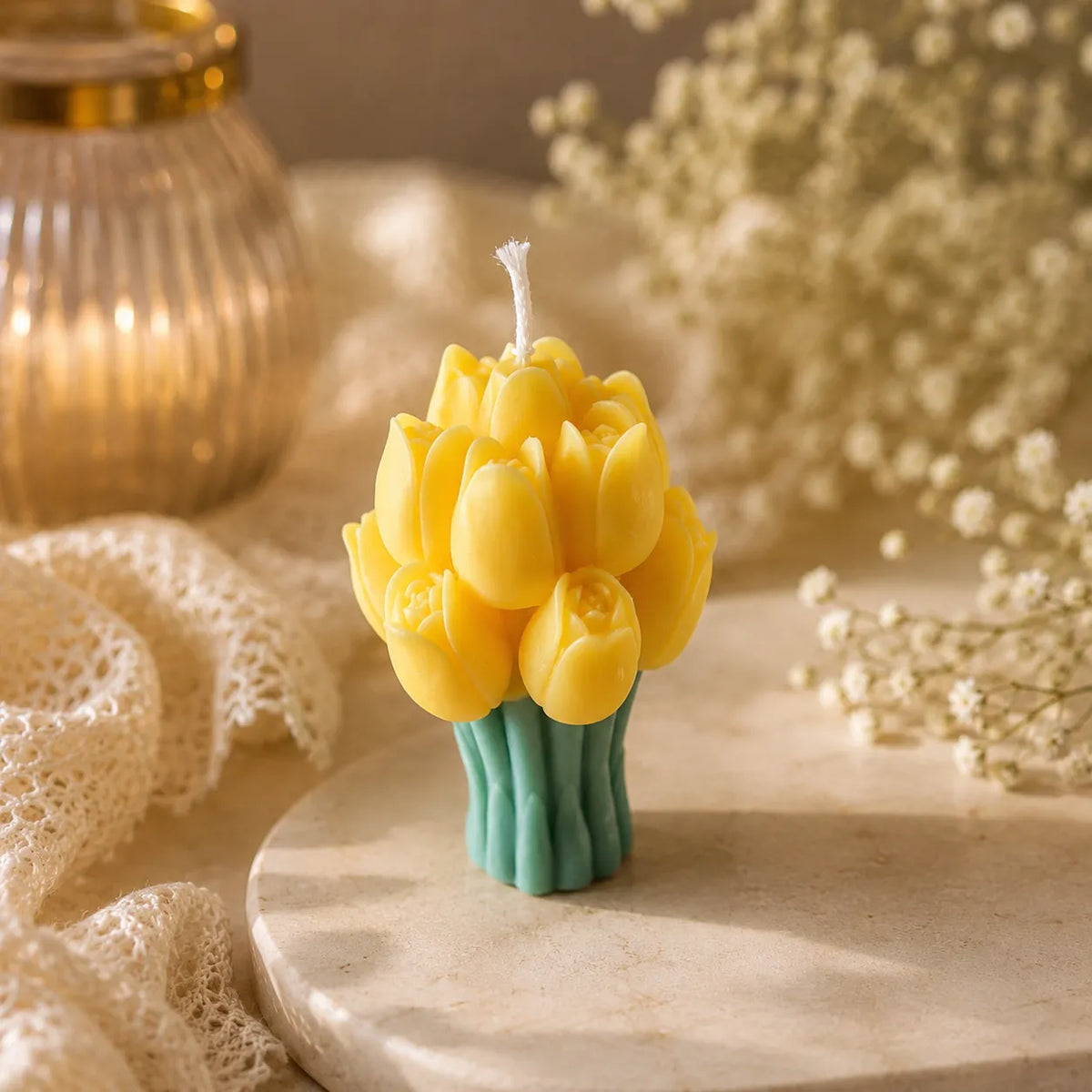Yellow tulip-shaped candle on a marble surface with a blurred background