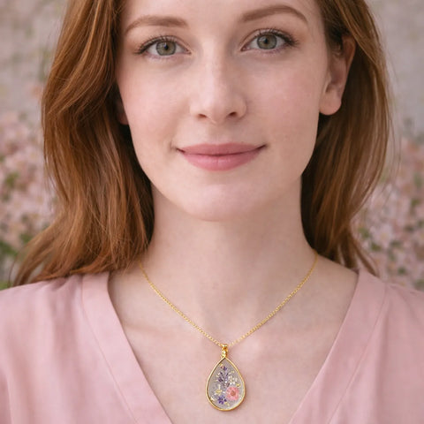 Woman wearing a gold necklace with a floral pendant against a blurred floral background