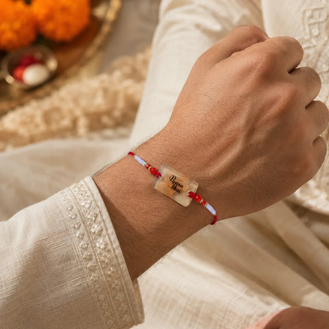 Hand wearing a bracelet with a decorative stone, set against a blurred background.