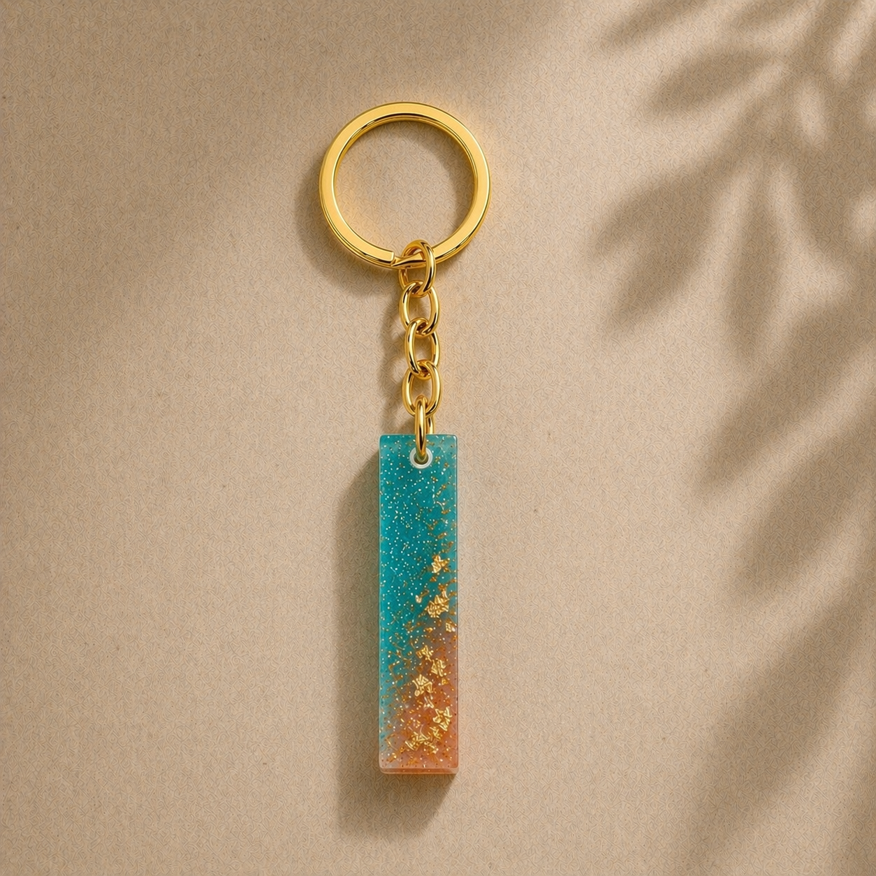 Gold keychain with a blue and orange striped pendant on a beige background