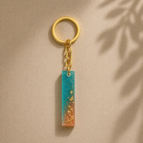 Gold keychain with a blue and orange striped pendant on a beige background