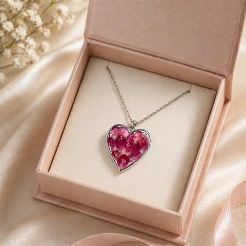 Heart-shaped floral pendant necklace in a pink jewelry box with baby's breath flowers.