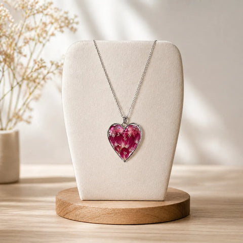 Necklace with a pink heart-shaped pendant on a white bust against a neutral background