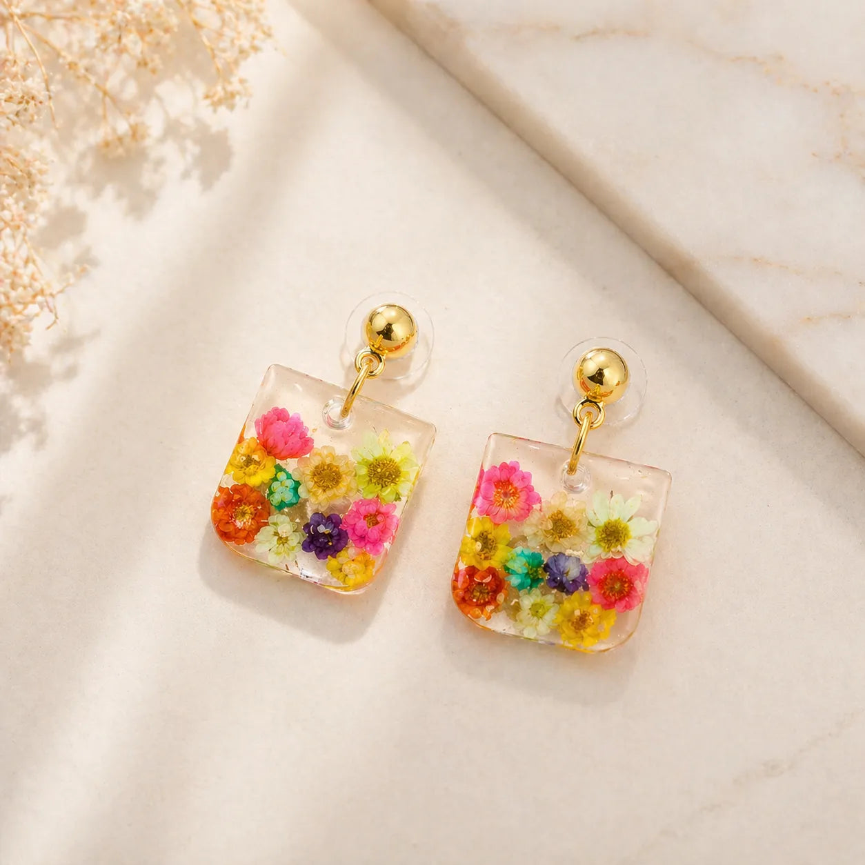 Colorful floral earrings on a light background
