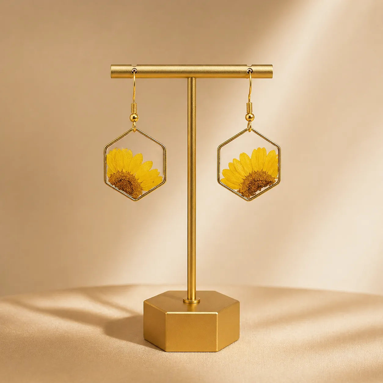 Gold earring stand with sunflower earrings on a beige background