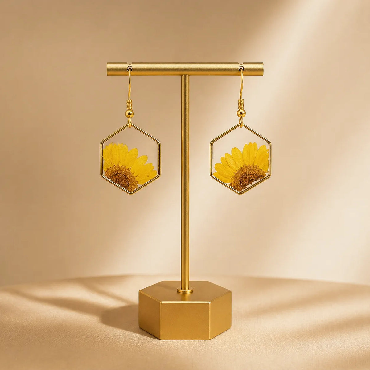 Gold earring stand with sunflower earrings on a beige background