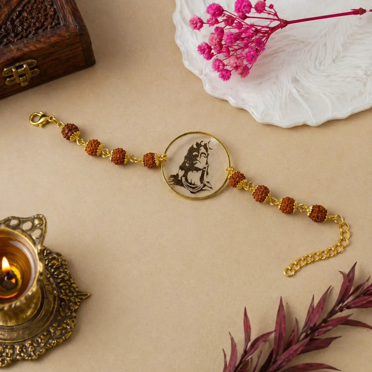 Bracelet with decorative elements on a beige surface with flowers and a candle.