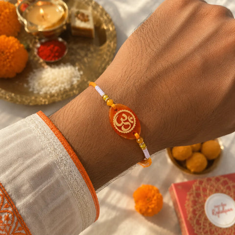 Hand wearing a bracelet with an 'Om' symbol, surrounded by decorative items on a table.