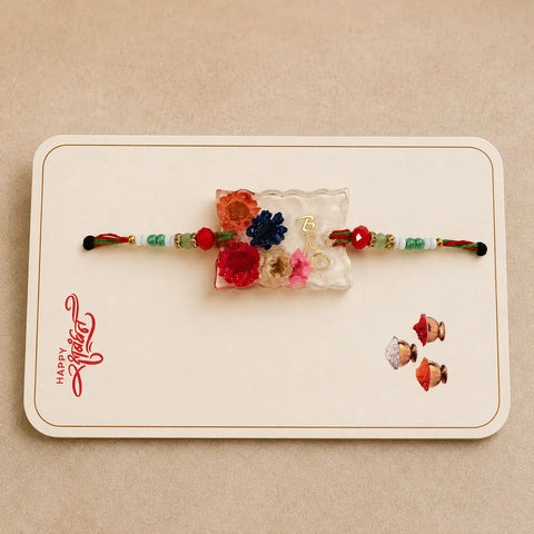 Two floral-themed bracelets on a 'Happy Rakhi' card with cartoon characters on a beige background.