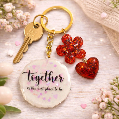 Keychain with floral charm and motivational quote on a light wooden surface with flowers.