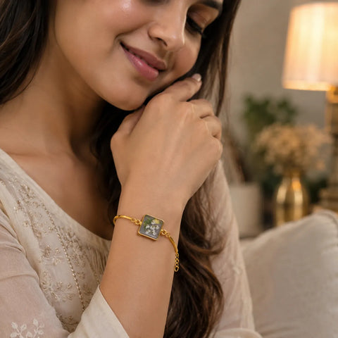 Woman wearing a gold bracelet with a decorative clasp in a warm indoor setting.